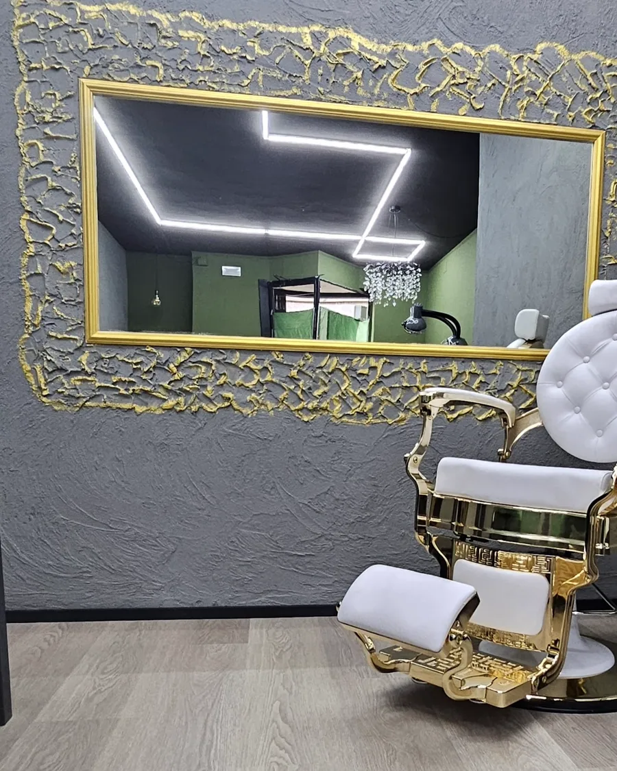 Lo specchio con cornice dorata e la parete materica del salone